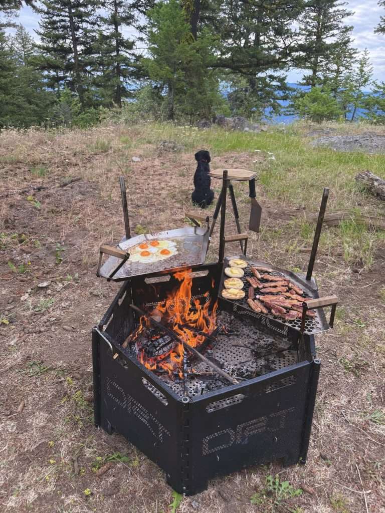 Cooking-eggs-sausage-muffin-bacon-breakfast-over-campfire-camping-road-grill-firepit