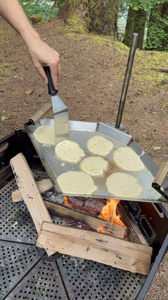 Cooking-pancakes-over-fire-campfire-from-scratch-bubbling-batter-flapjacks-crepes-camping-on-the-road-grill-dirt-road-tools