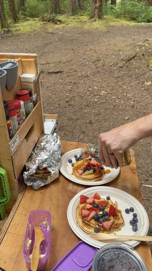 Drizzling-Canadian-Maple-Syrup-on-Homemade-Pancakes-topped-with-fresh-berries-Made-While-Camping